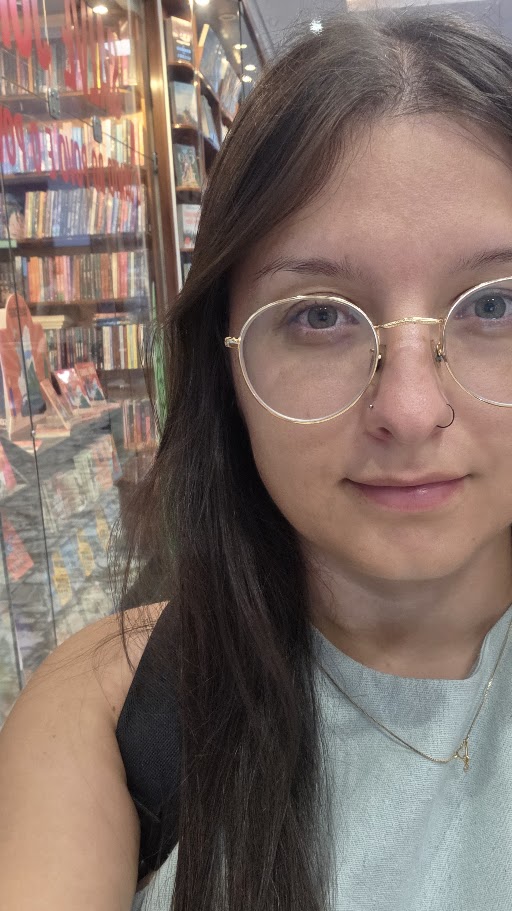 Jess, de óculos, em frente a uma estante de livros